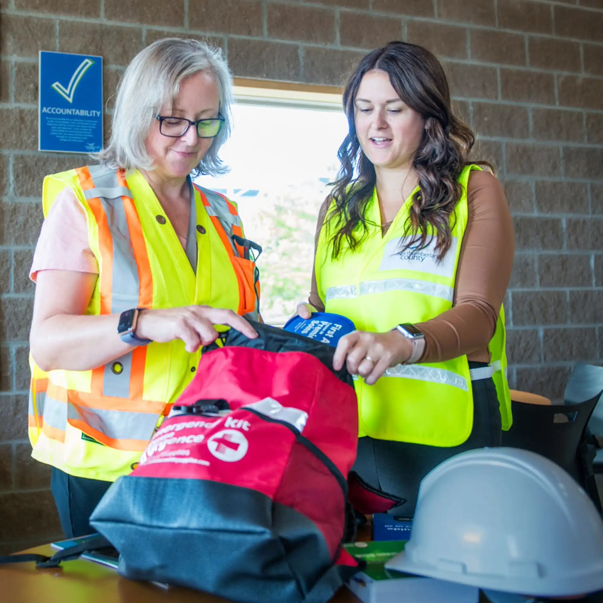 Two staff members look through a 72-hour emergency kit
