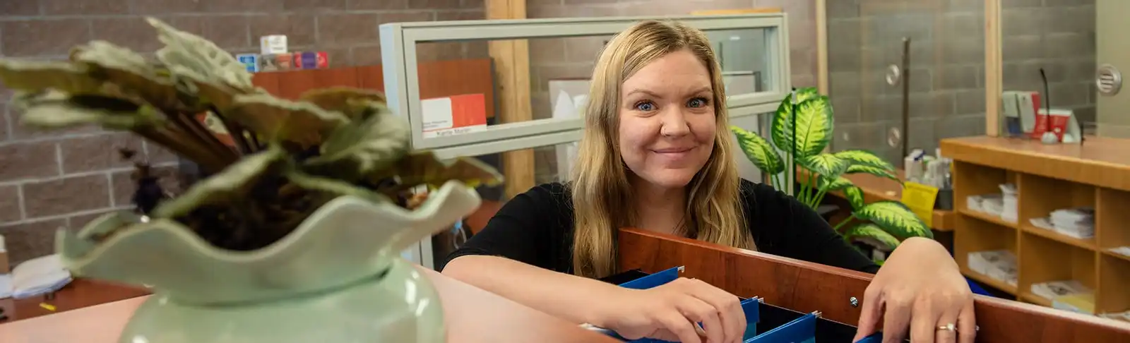 HR staff smiles while looking through file drawer