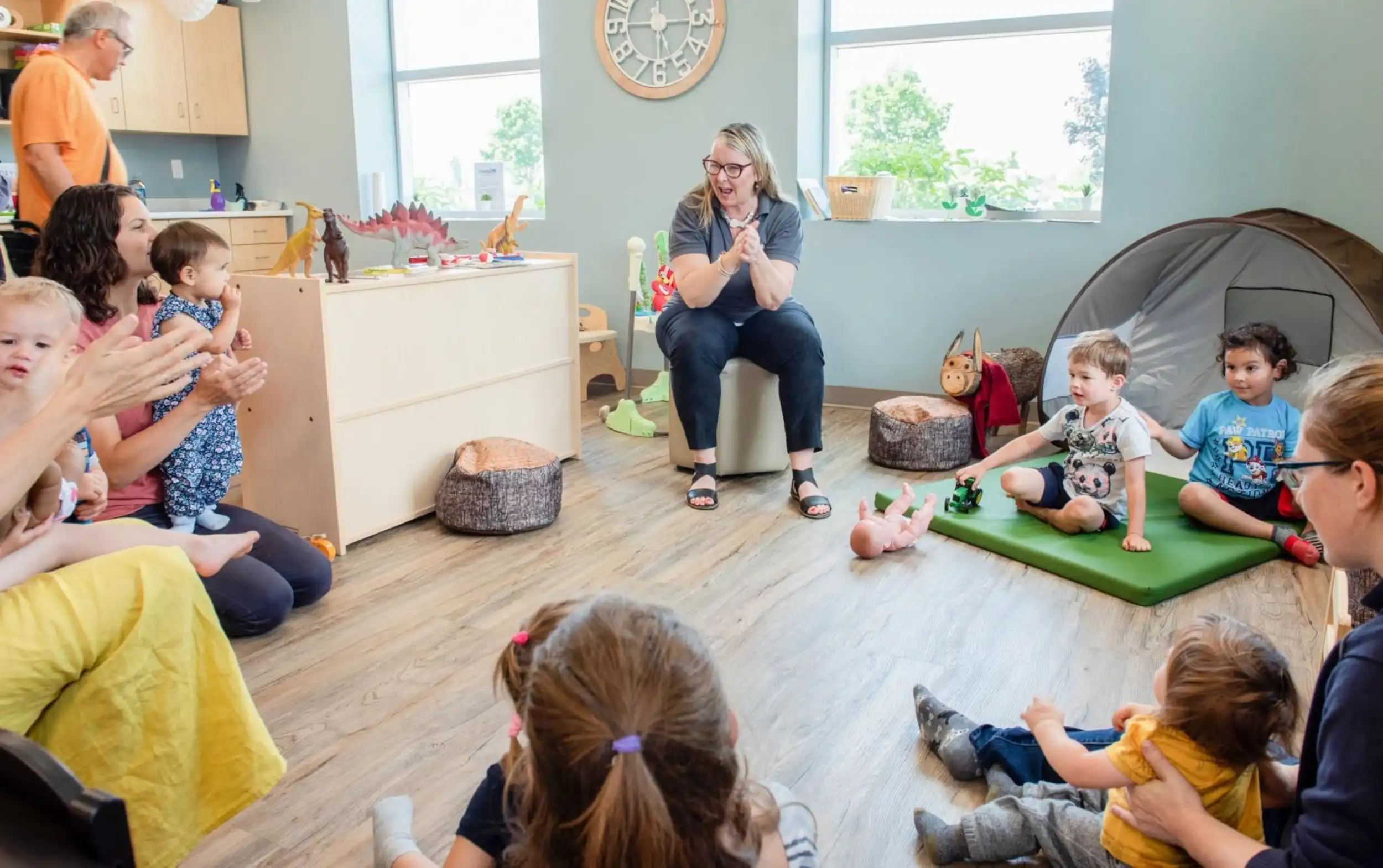 Early childhood educator sitting in a circle with children and families during an activity.