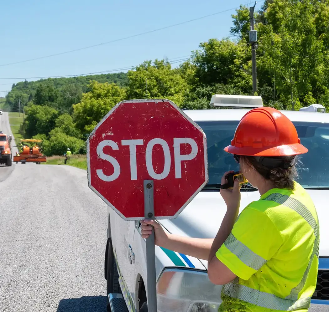 Staff holding up stop sign at road work site