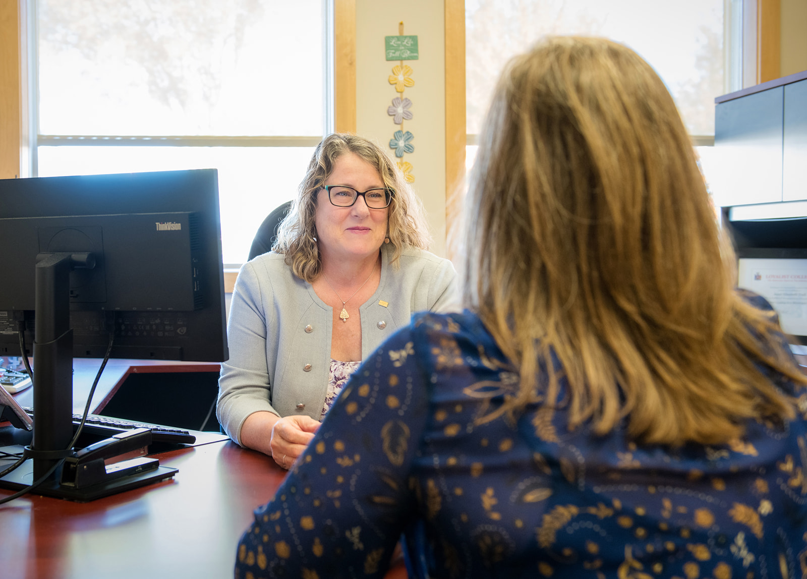 Accessibility Coordinator smiles at staff sitting across from them in their office
