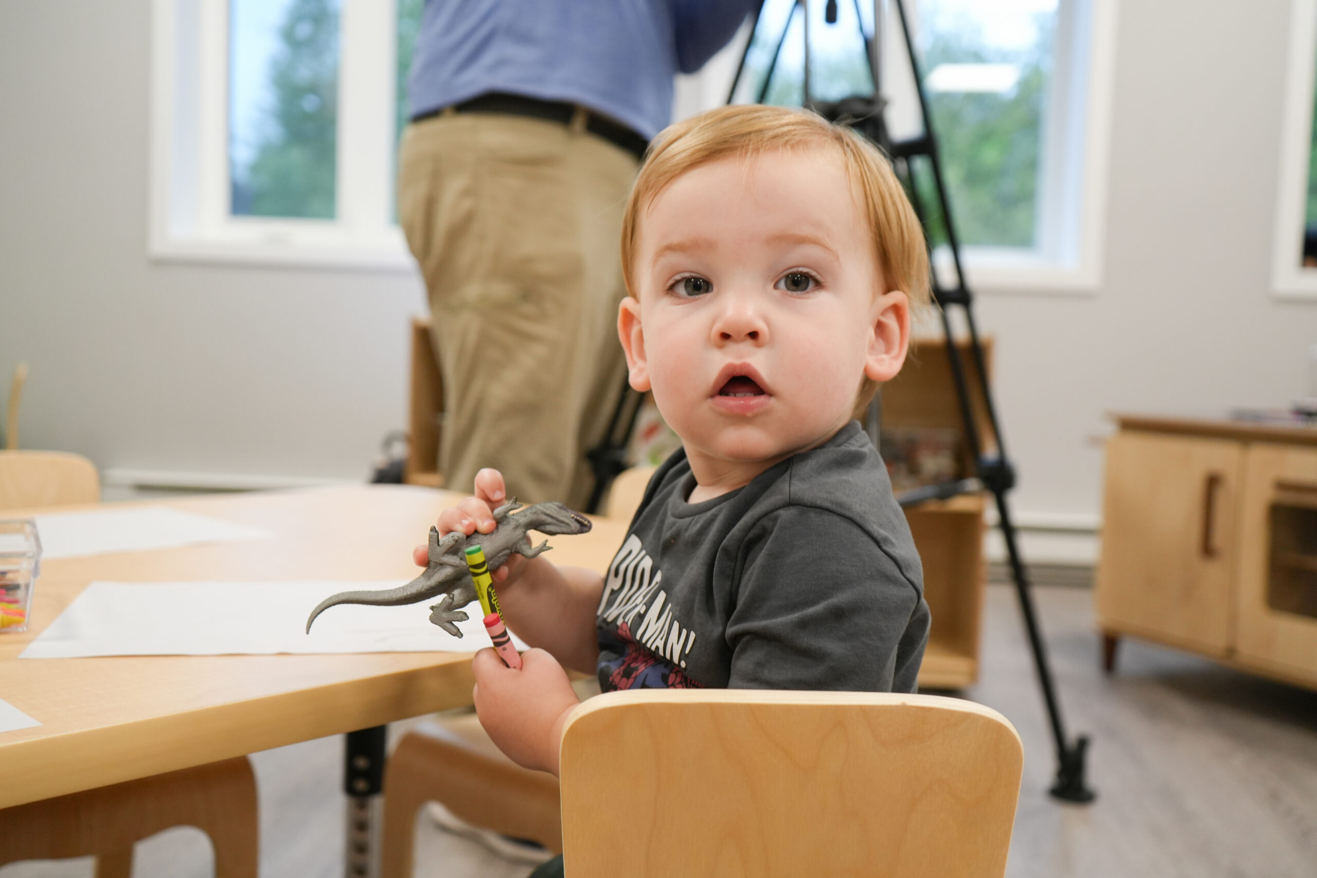 Little boy looks at camera as he holds a dinosaur toy