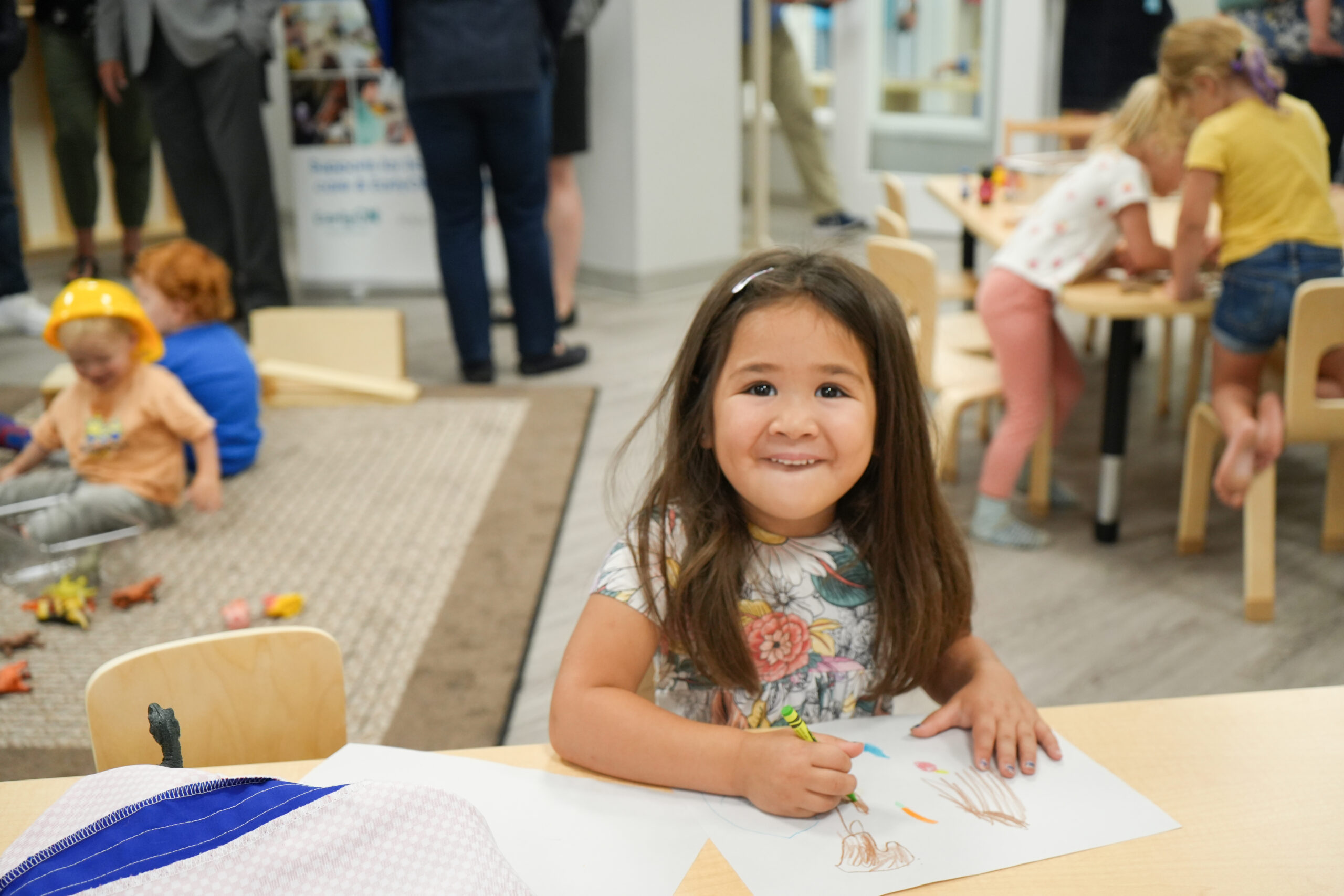 Girl smiles at camera as she draws
