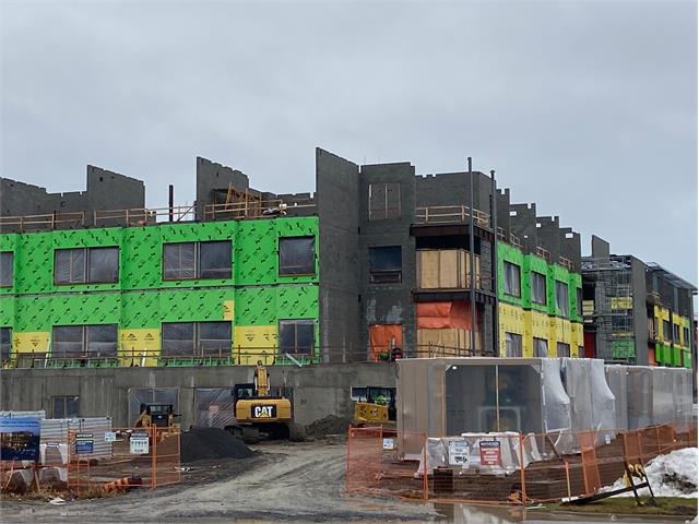 Side view of the building under construction with building materials lining the side of the wall.