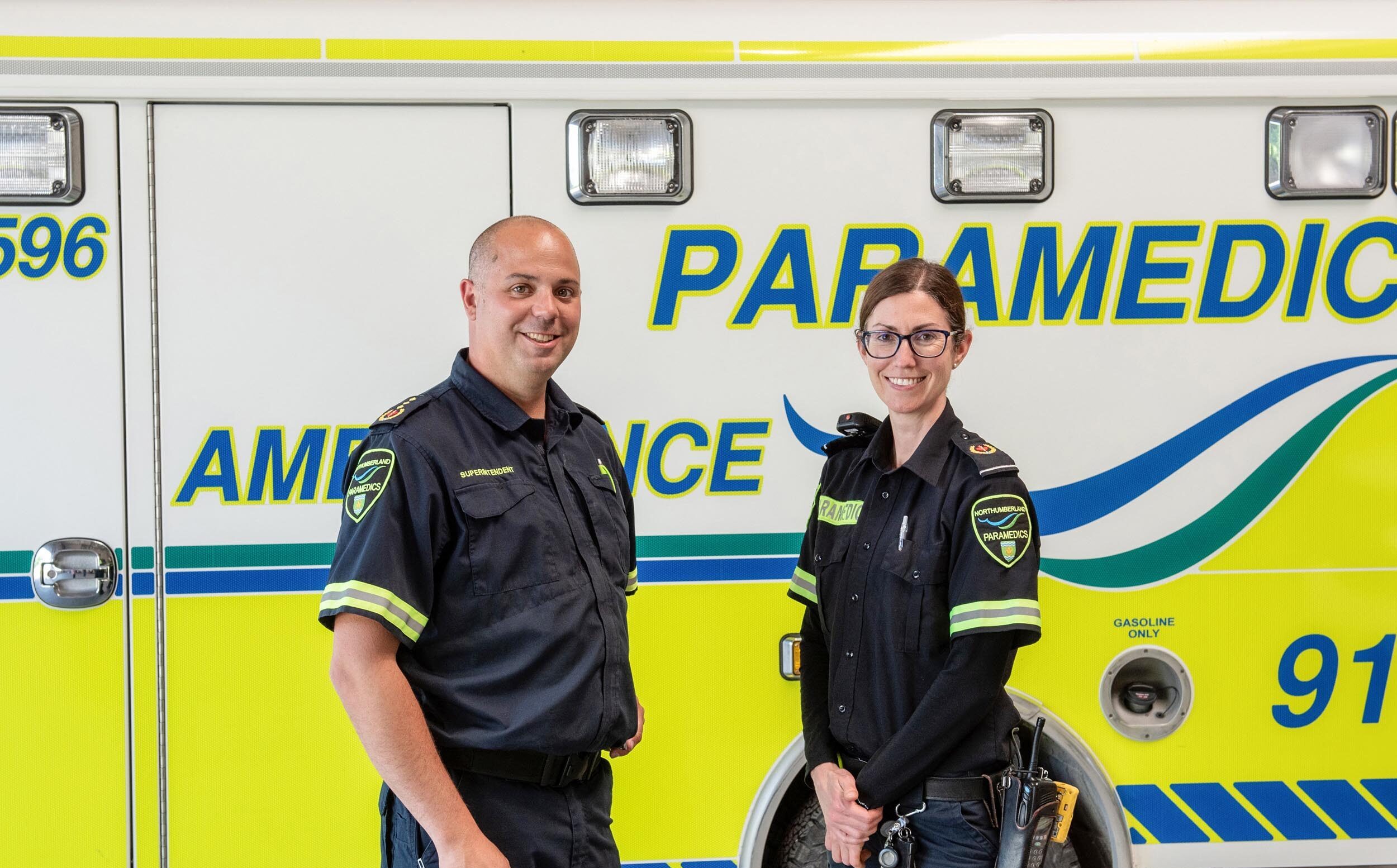 Two paramedics stand in front of ambulance