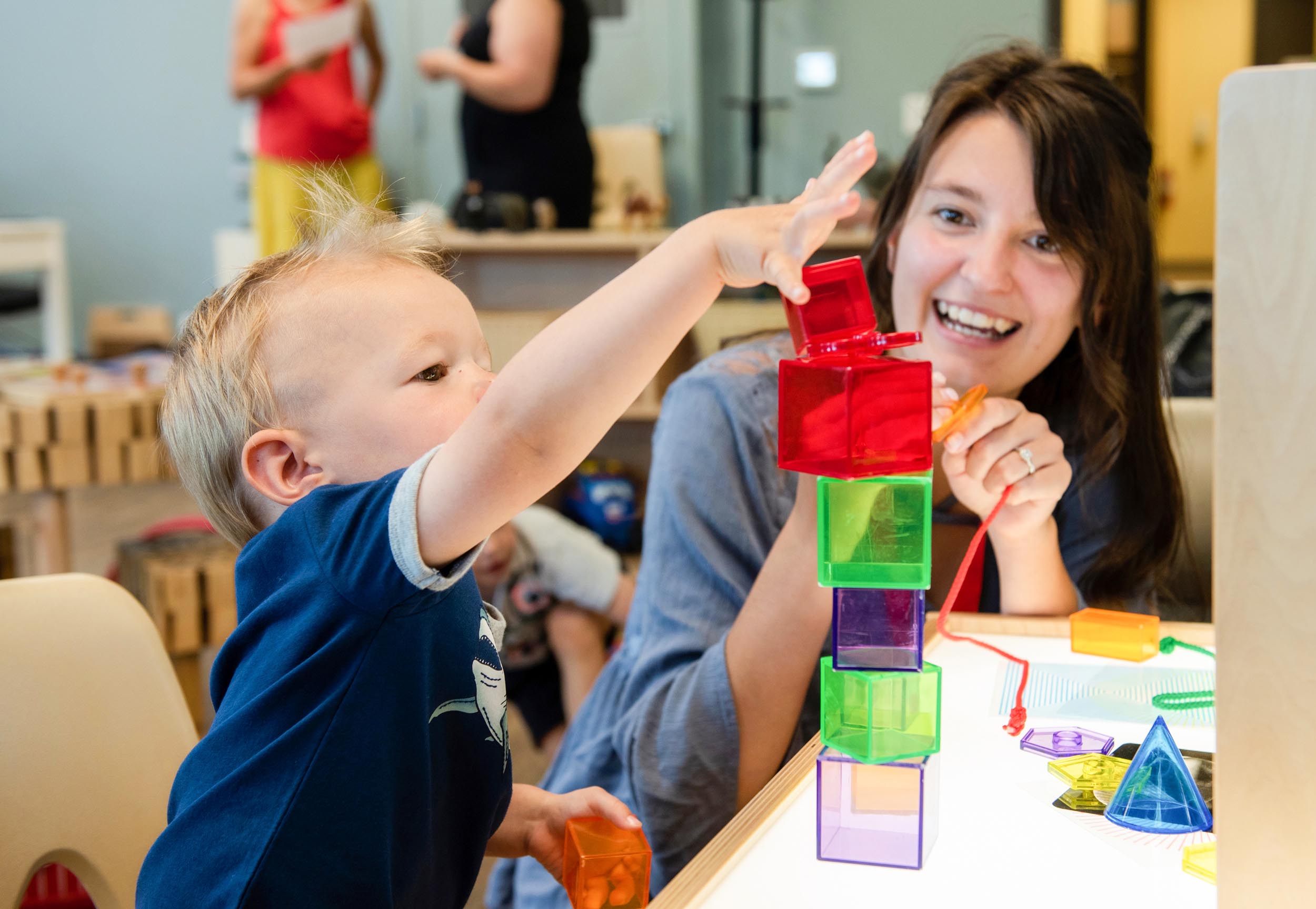Woman plays with toddler stacking building blocks