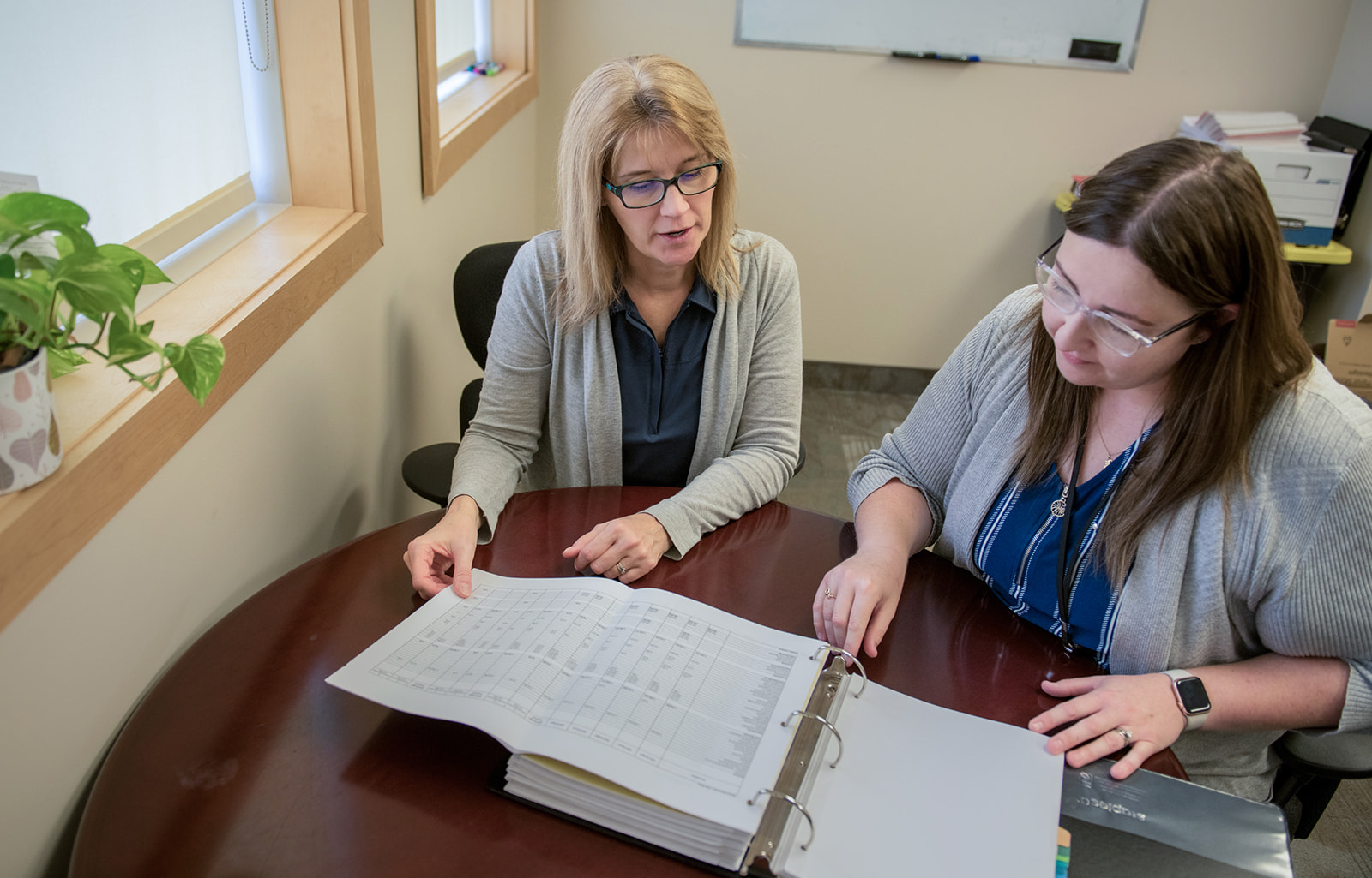 Two staff look at a budget binder