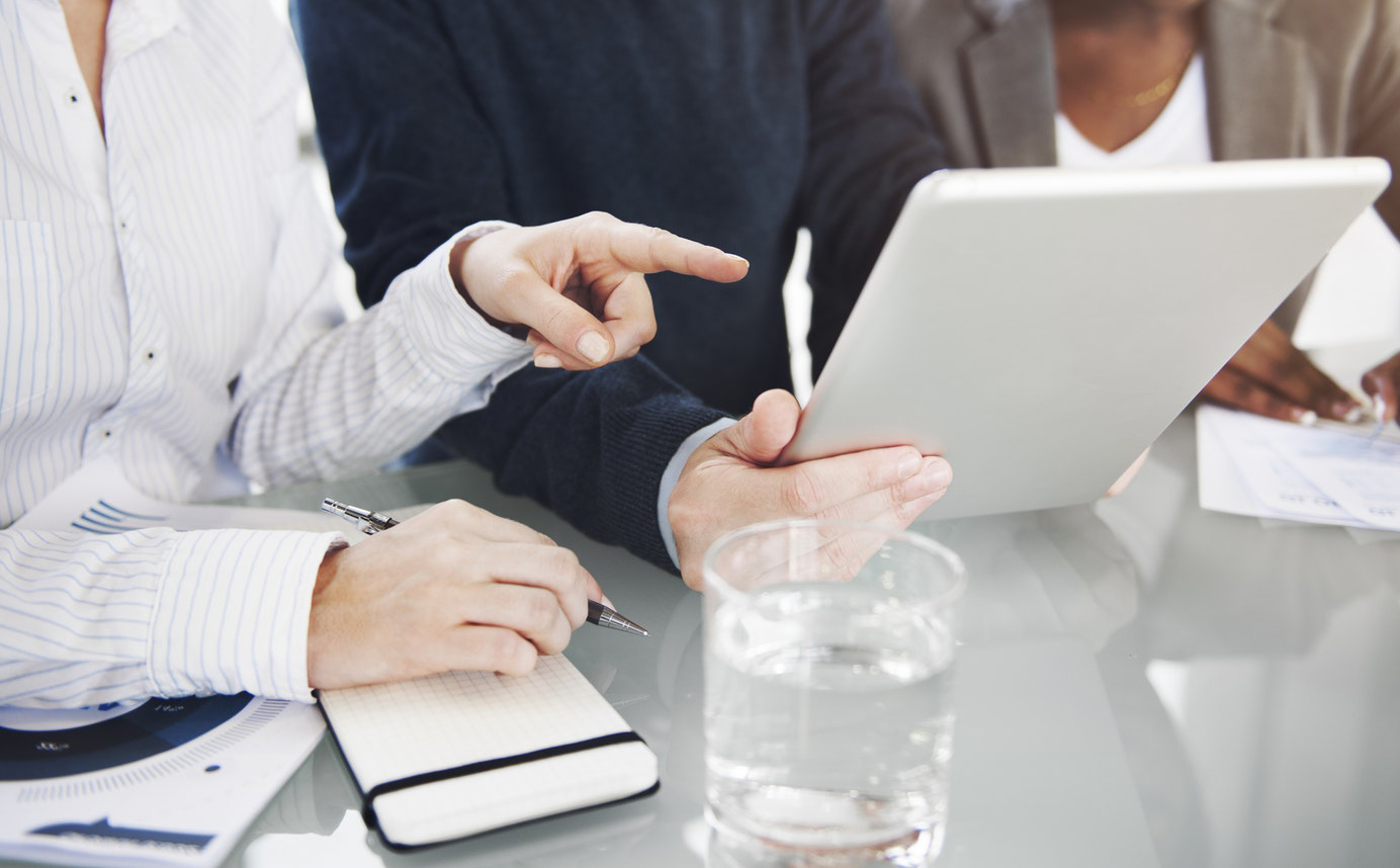 someone points at a report on another person's tablet
