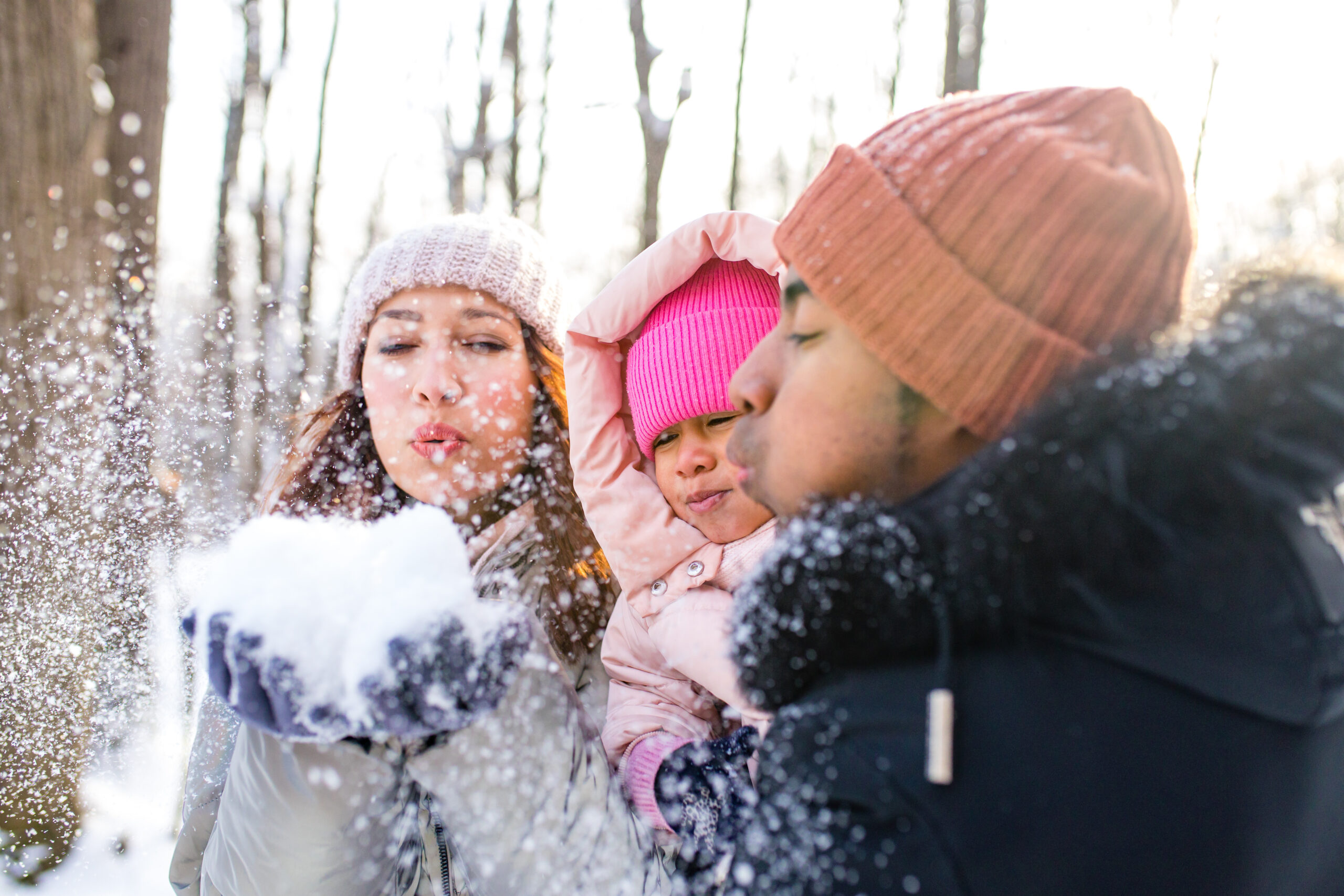 Two parents outside with a young child on a snowy day.