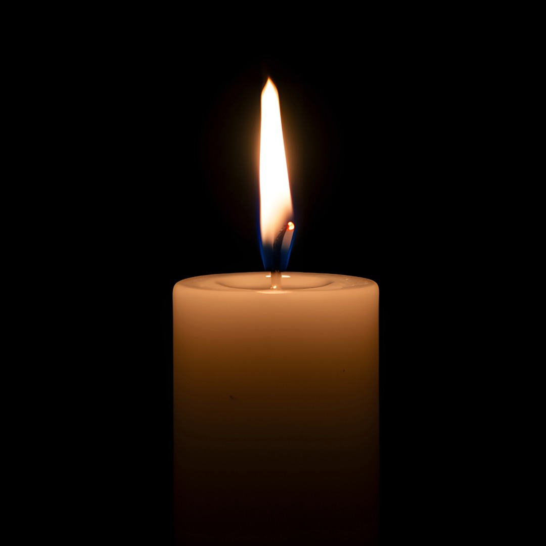 Single candle burning in a dark room.